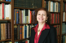 Foto da Professora Vivina Rios em frente a uma estante de livros