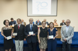 Imagem: Fotos dos familiares do grupo médico responsável pela criação do Curso de Medicina com placas de homenagem nas mãos