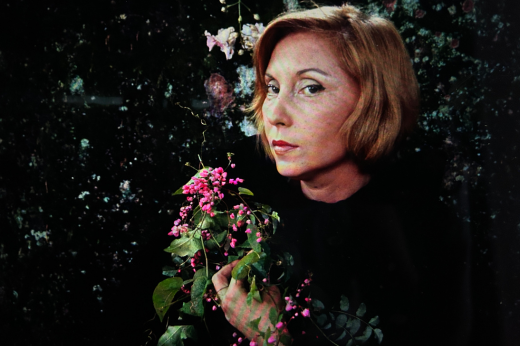 Clarice Lispector segurando flores nas mãos e olhando fixo para a câmera