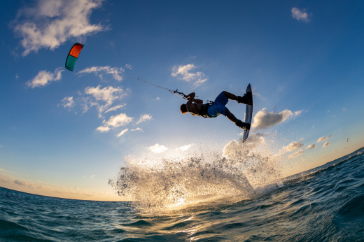 Homem em cima da prancha de kitesurf em alto mar