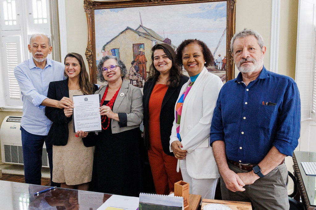 Imagem: Participantes da reunião sorriem e seguram o termo de apoio ao projeto Diagnóstico da Erosão Costeira no Município de Jijoca de Jericoacoara (CE). São eles: Inácio Arruda, Germana Pires, Diana Azevedo, Lidriana Pinheiro, Sandra Monteiro e Alexandre Medeiros de Carvalho.
