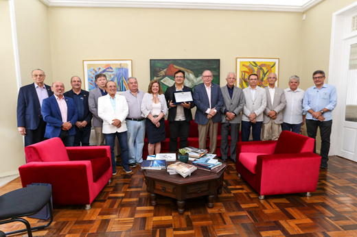 Imagem: Treze homens e uma mulher posam, de pé, no Gabinete da Reitoria. Ao centro, estão o reitor Custódio Almeida e o presidente da FIEC Ricardo Cavalcante.