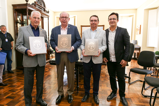 Imagem: Reitor Custódio Almeida entrega exemplares do livro da Caravana UFC 70 Anos a três dirigentes da FIEC.