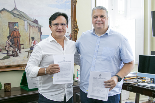 Imagem: De pé, no Gabinete da Reitoria, o reitor Custódio Almeida e o secretário João Pupo seguram o documento assinado. (Foto: Álvaro Graça Jr./UFC Informa)