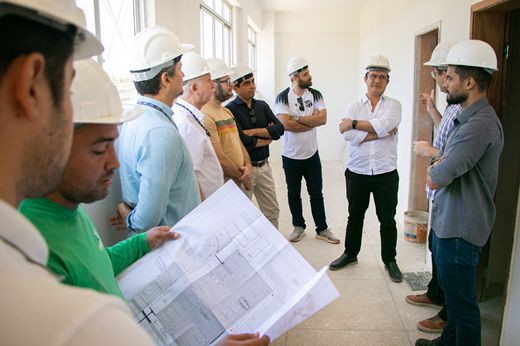 Dez homens usando capacetes visitam a obra da Central Analíticas; dentre eles, estão o reitor Custódio Almeida, os coordenadores da Central Antonio Gomes e Emilio Miguel, e o superintendente de Infraestrutura Renato Guerreiro. (Foto: Ribamar Neto/ UFC Informa) 