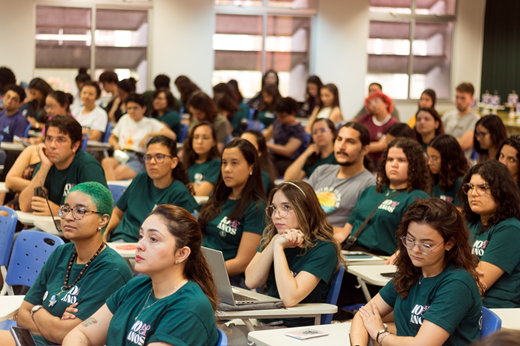 Imagem: Foto mostra a plateia assistindo ao evento; o público é majoritariamente feminino.