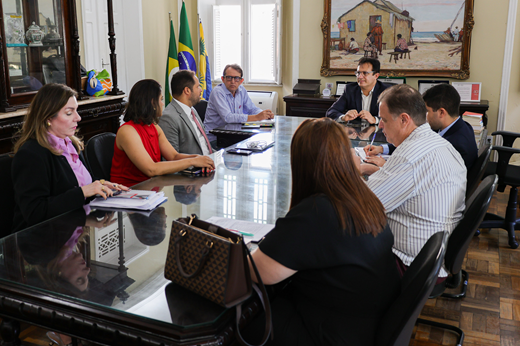 Imagem: Sentados à mesa, estão a comitiva do TRE-CE, o Chefe de Gabinete da Reitoria Prof. Carlos Almir Monteiro e o reitor Custódio Almeida. 