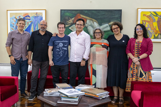 De pé, da esq. para a dir.: Prof. Estêvão Rolim (pró-reitor adjunto de Extensão), Prof. Sandro Gouveia (pró-reitor de Cultura), Júlio Brizzi (secretário de Juventude), Prof. Custódio Almeida (reitor da UFC), Profª Bernadete Porto (pró-reitora de Extensão), Profª Glícia Pontes (pró-reitora adjunta de Cultura) e Simone Faustino (comunicação de gestão do Gabinete da Reitoria). (Foto: Guilherme Silva/ UFC Informa)