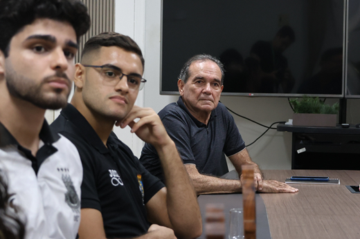 O secretário de Esportes da UFC, professor Antônio Lima, defendeu diante da Reitoria investimentos e interiorização para o desporto universitário. (Foto: Viktor Braga/ UFC Informa) Imagem: Plano fechado de dois estudantes e do secretário Antônio Lima