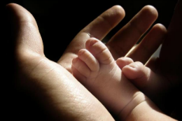 Imagem: Pequenino pé de bebê na mão de um adulto