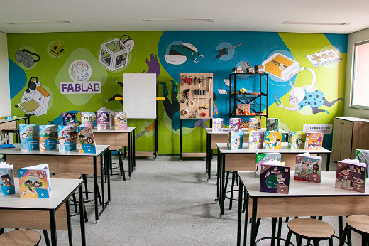 Imagem: Foto de uma das salas internas do CEnPE com paredes coloridas e escrivaninhas repletas de livros infantis