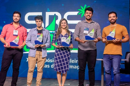 Imagem: Foto posada de cinco pessoas recebendo troféus com os prêmios para os melhores trabalhos apresentados no Simpósio Brasileiro de Sistemas de Informação