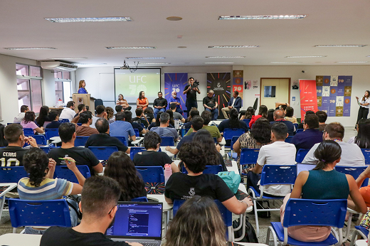 Imagem: Reitor Custódio Almeida falando em um auditório, com muitas pessoas presentes (Foto: Ribamar Neto/UFC)