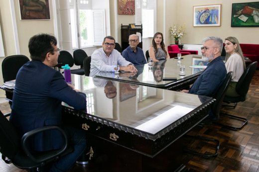 Imagem: Participantes da reunião sentados na mesa principal do Gabinete da Reitoria