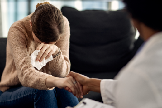 Imagem: Mulher chorando de cabeça baixa em consultório 