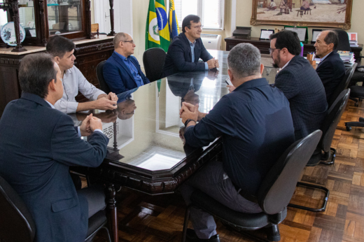 Pessoas sentadas na mesa da Reitoria em reunião com o reitor