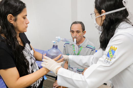 Imagem: Fisioterapeuta em primeiro plano fazendo exercícios de respiração em paciente 