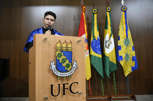 Imagem: Homem discursa em um púlpito com o brasão da UFC vestindo traje talar (Foto: Viktor Braga/UFC Informa)