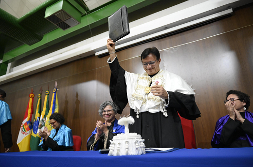 Imagem: Reitor Custódio Almeida levanta documento que certifica a conclusão do curso dos estudantes (Foto: Viktor Braga/UFC Informa)