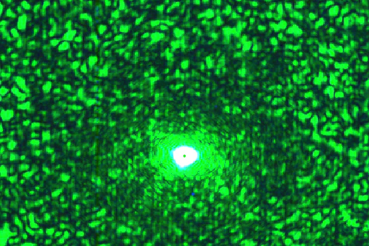 Imagem: Imagem com fundo verde, mostra laser sendo aplicado sobre quartzo e se espalhando sobre rochas (Divulgação/Felipe Aires)