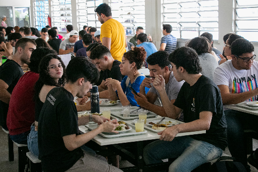 Imagem: Foto mostra grupo de jovens reunidos em torno de uma mesa no Restaurante Universitário enquanto almoçam (Foto: Ribamar Neto/UFC Informa)