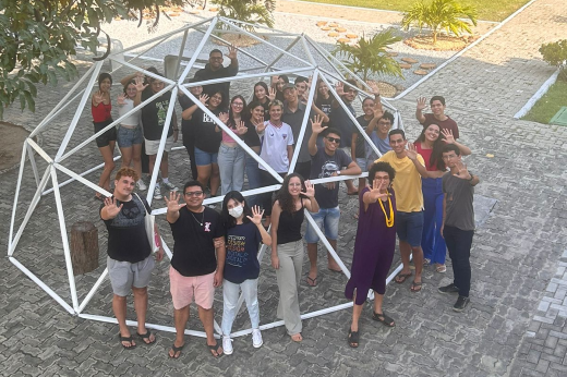 Imagem: Foto feita do alto mostra grupo de estudantes dentro de uma peça metálica vazada, com os cinco dedos da mão espalmados em referência à nota cinco (Foto: Divulgação Campus de Quixadá)