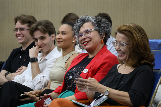 Imagem: cinco pessoas aparecem sentadas em poltronas de um auditório, uma ao lado da outra, sendo dois rapazes brancos jovens, uma mulher negra jovem e duas mulheres mais velhas, uma delas a vice-reitora da UFC, Diana Azevedo 